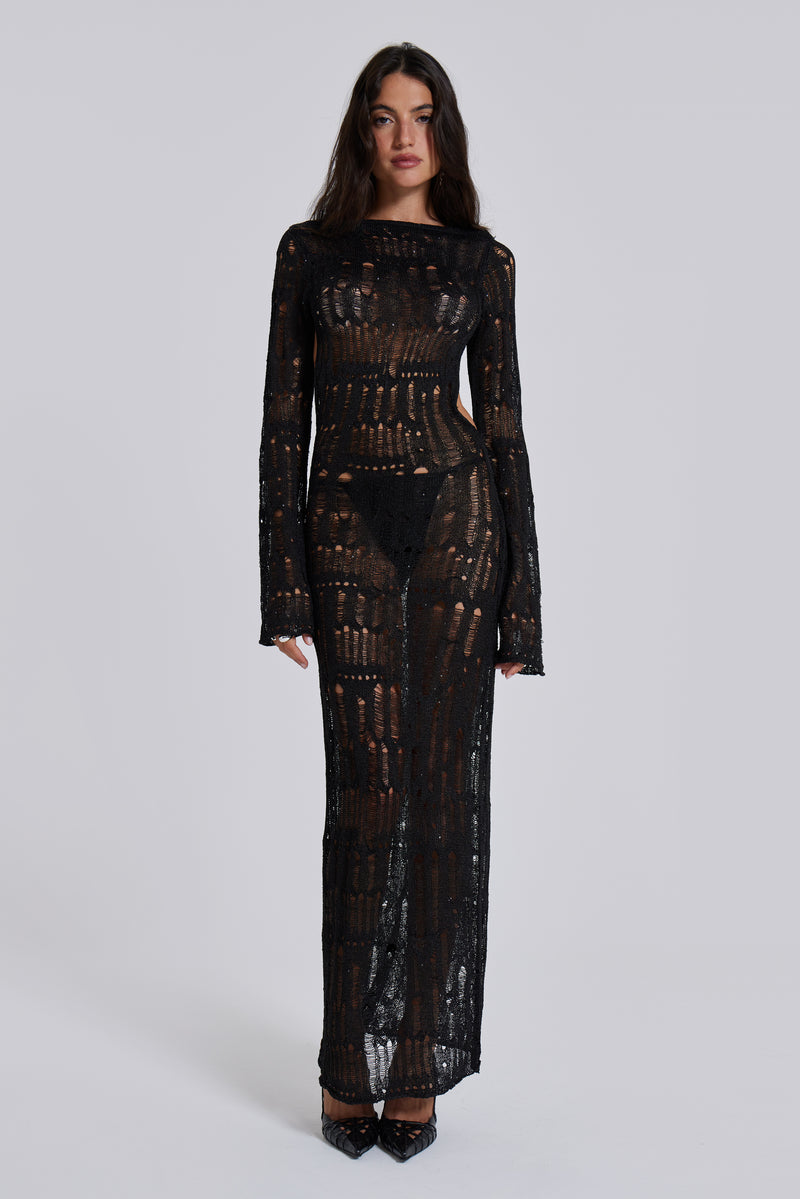 Female model wearing a black shredded, laddered knitted long sleeve maxi dress with sequin details. 