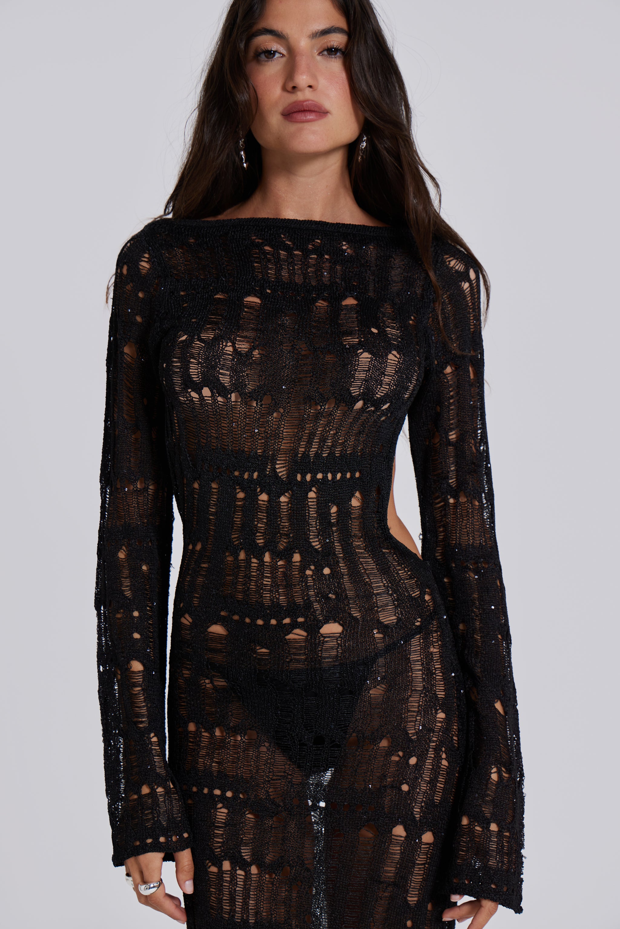 Female model wearing a black shredded, laddered knitted long sleeve maxi dress with sequin details. 