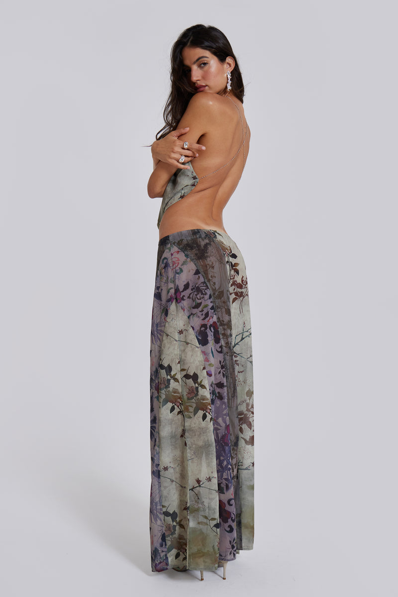 Female model wearing a floral cowl neck backless top with a halter neck chain fastening. Styled with the matching maxi length skirt. 