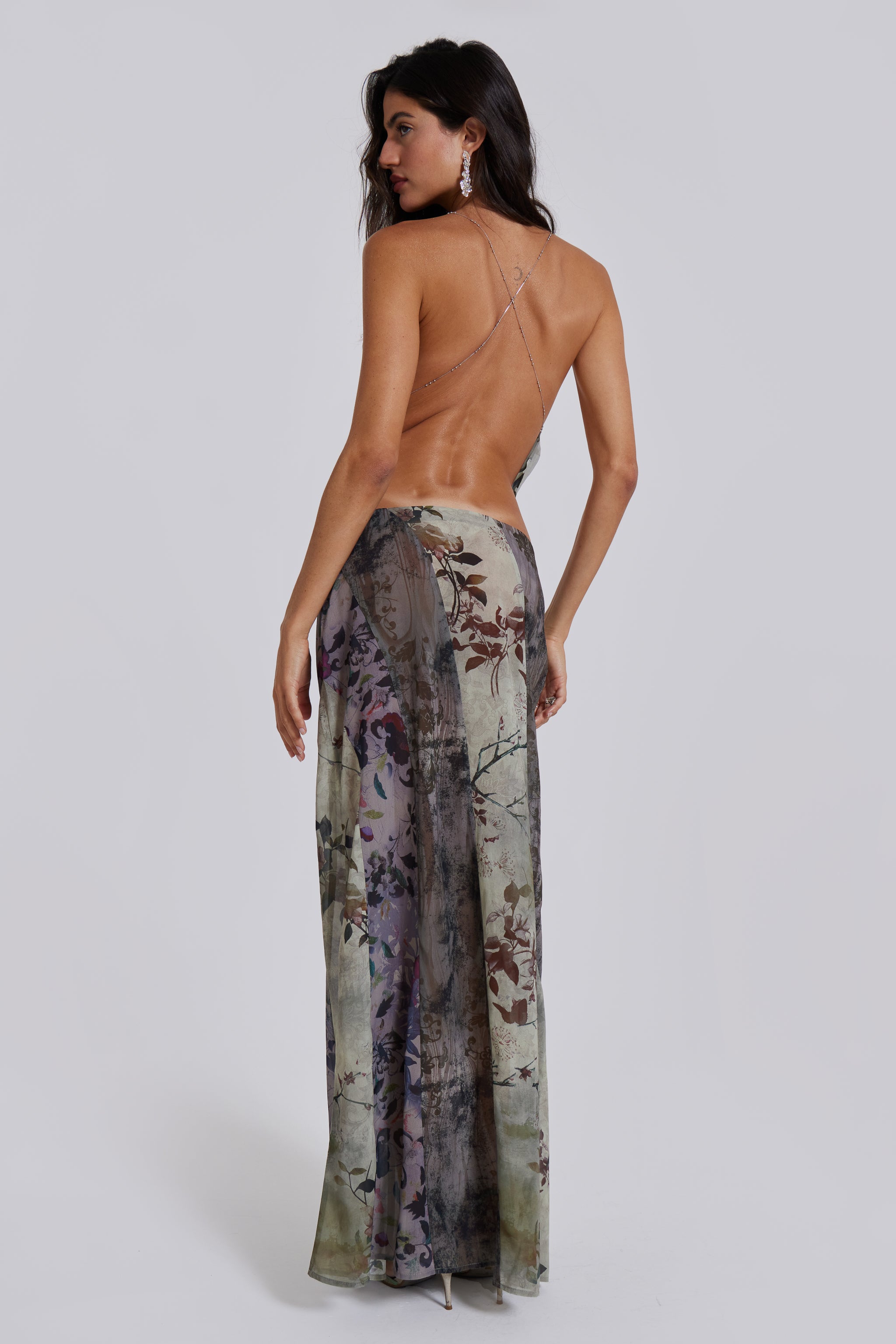 Female model wearing a floral cowl neck backless top with a halter neck chain fastening. Styled with the matching maxi length skirt. 