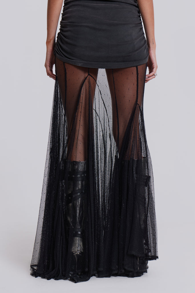 Female model wearing a sheer mesh maxi length skirt in black. Styled with a black and grey graphic one shoulder top. 