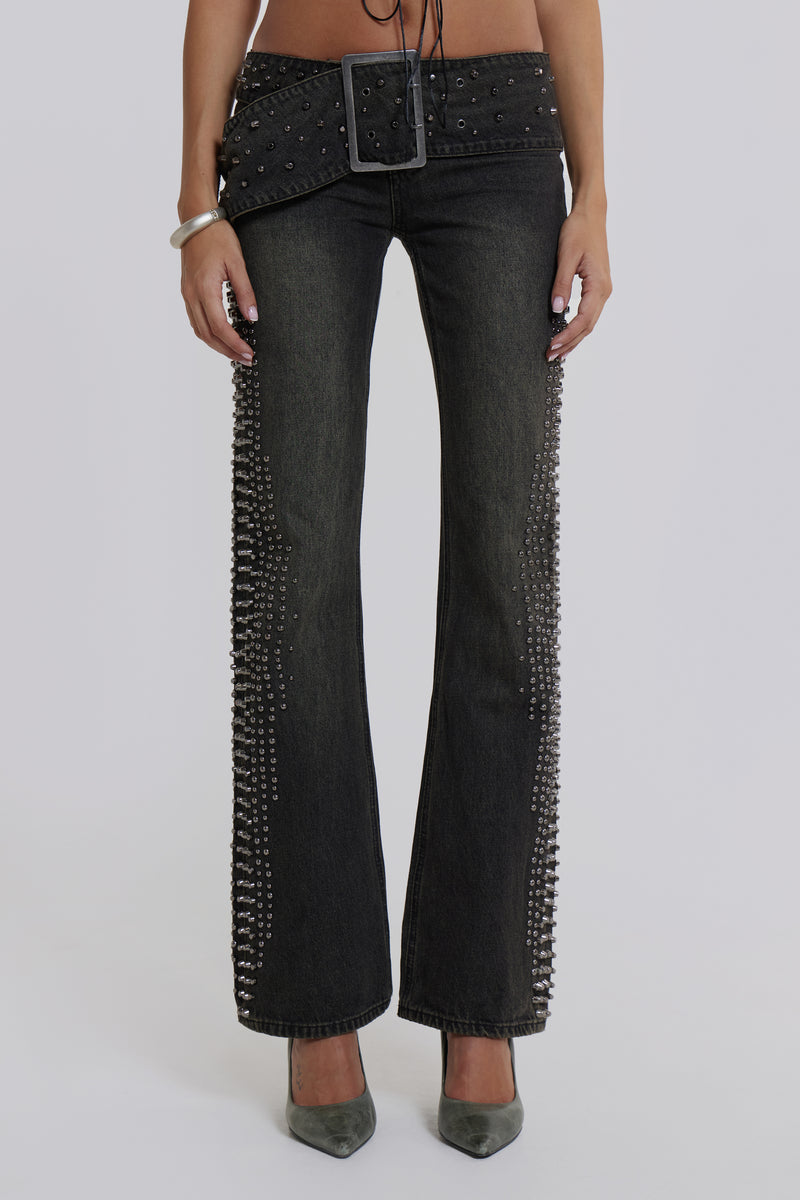 Female model wearing studded denim jeans with large buckle belt.
