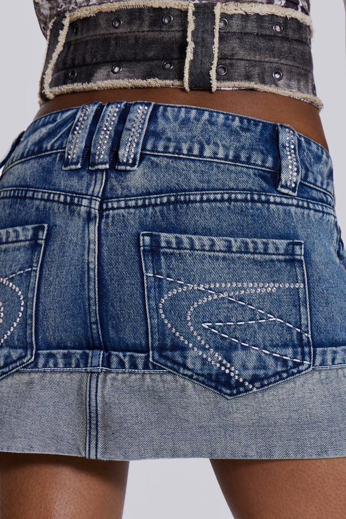 The Alexis Mini Skirt is crafted from a blue denim in a low-rise fit. The skirt features contrast stitching with an exaggerated turn-up out. The standout design is completed with functional zip pockets, diamante belt loops and exposed overlocked side seams.
