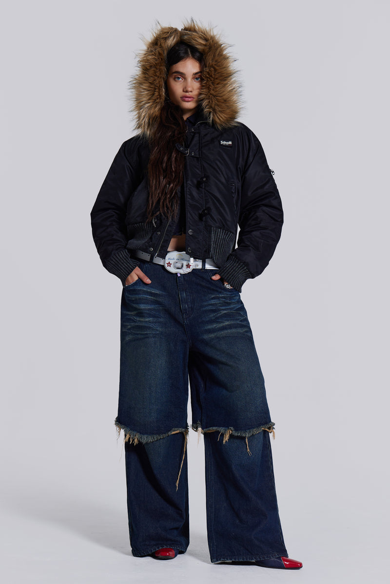  Female model wearing blue indigo baggy, loose fit denim jeans with a double layer effect. Styled with a black puffer coat. 