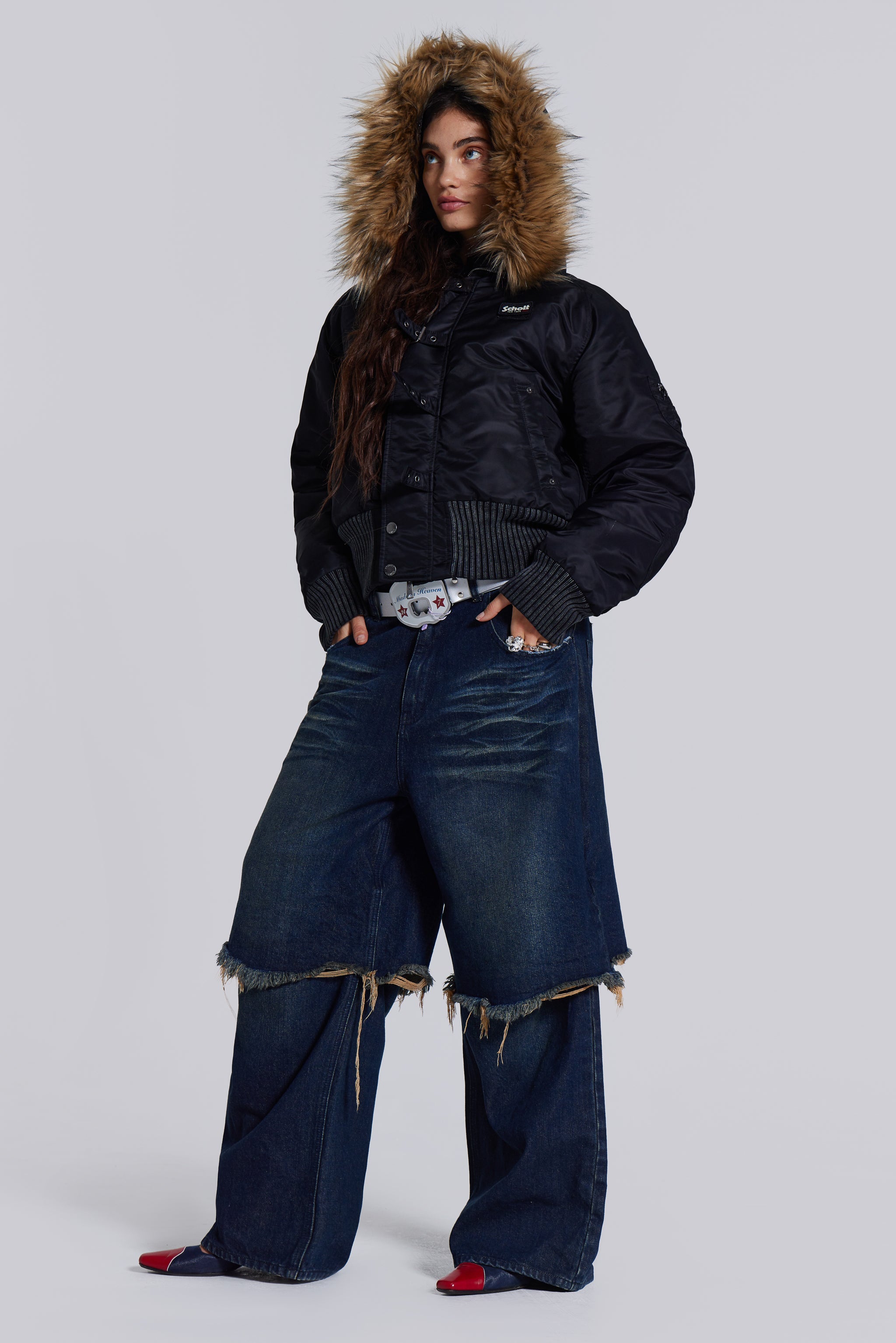  Female model wearing blue indigo baggy, loose fit denim jeans with a double layer effect. Styled with a black puffer coat. 