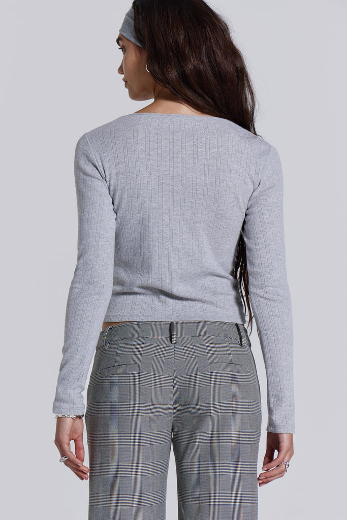 Female model wearing a grey marl long sleeve pointelle fabric with rib binding and needle neckline finish with a lace insert. 