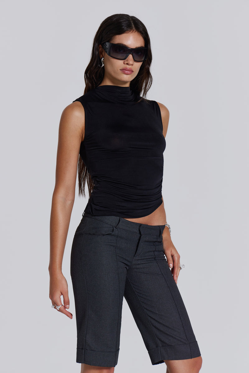 Female model wearing a black high neck top with a twisted back, asymmetric hemline detail and pleated side seam. Paired with charcoal grey tailored shorts. 