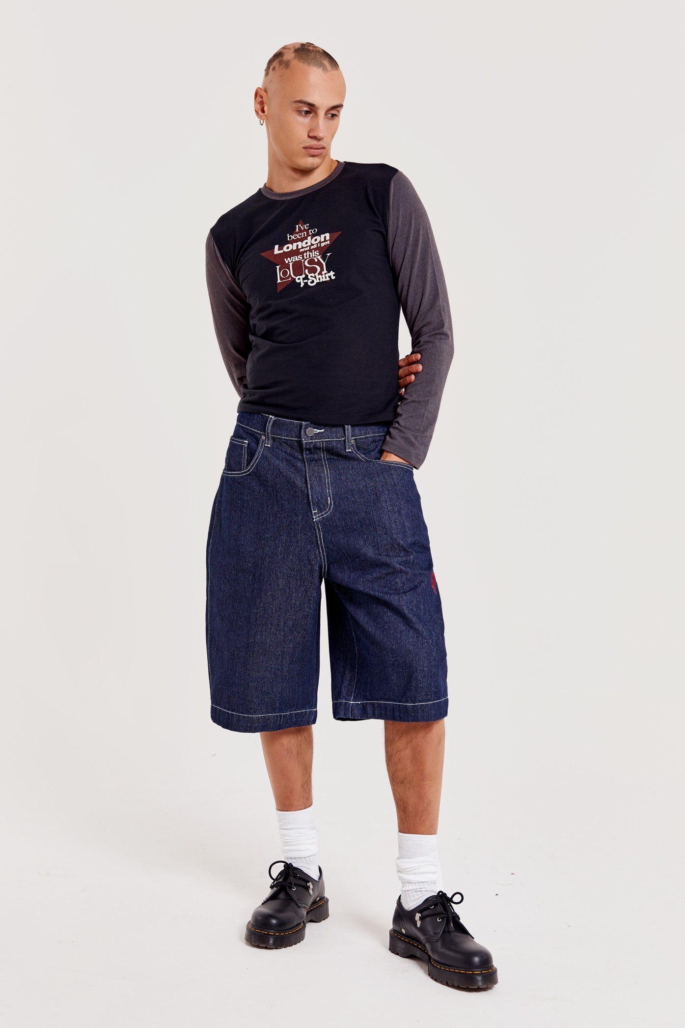 Male wearing indigo blue denim jorts in a jumbo fit with JL embroidered logo and Union Jack start branding on back pocket. 