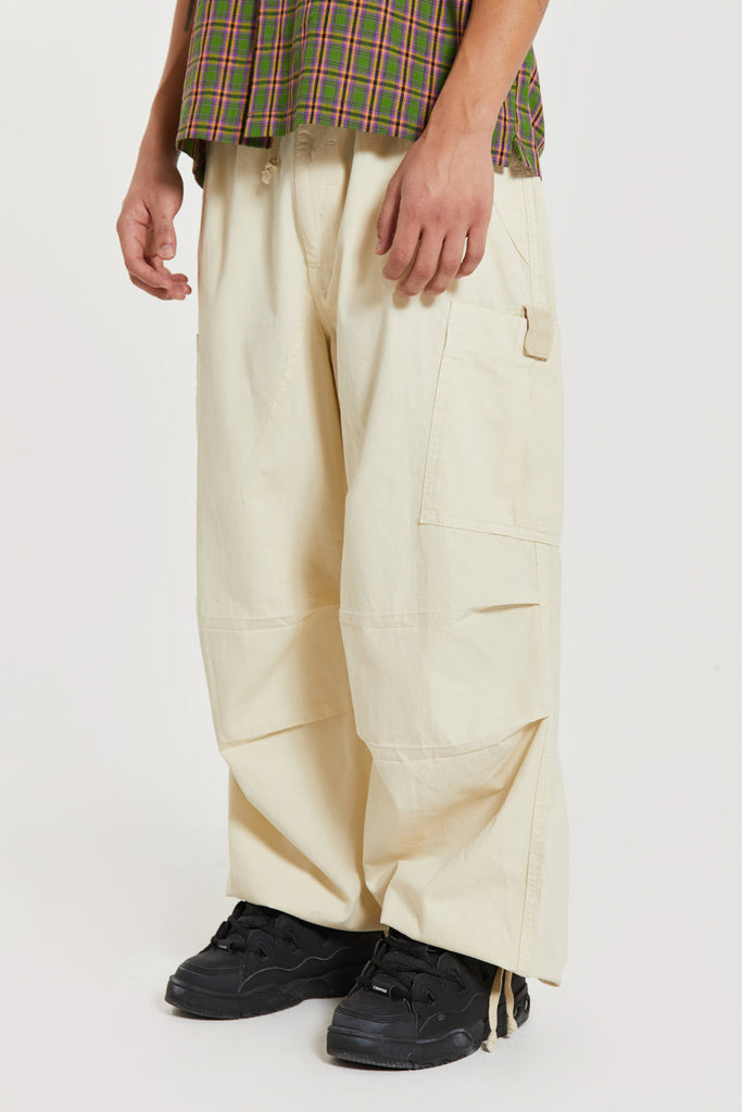 Unisex ecru oversized fitted parachute style cargo trousers with six pocket styling. 