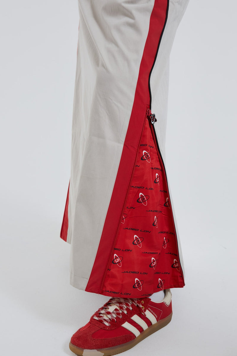 Female wearing red and almond track style midi length skirt with open zip detail.
