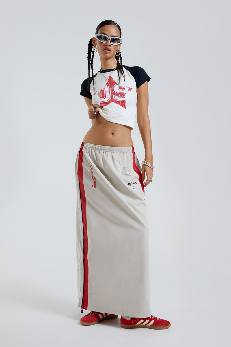 Female wearing red and almond track style midi length skirt. Styled with black and white crop top. 