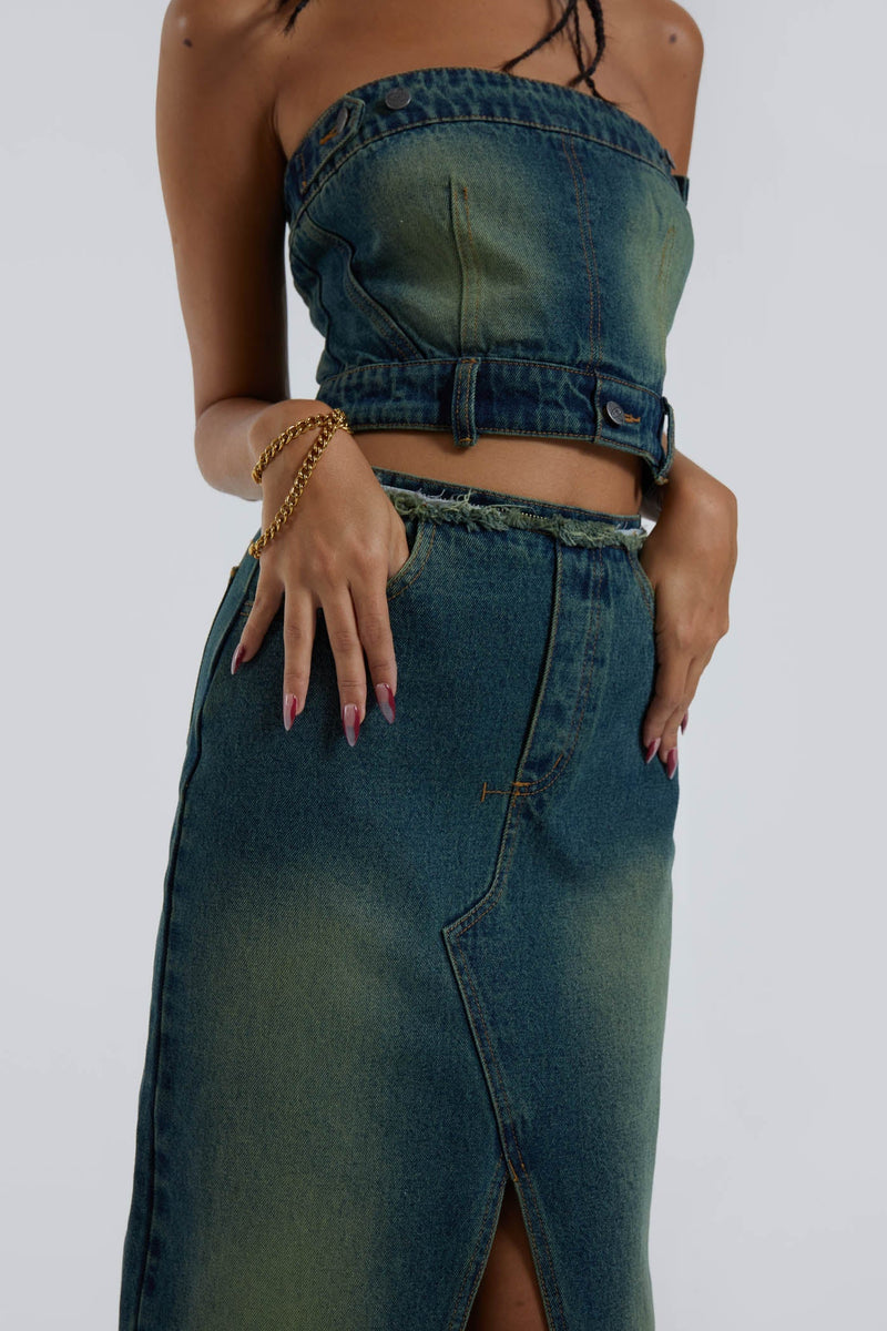 Female wearing blue bandeau denim corset maxi length dress with front split detail. Top and skirt has been zipped off to be worn as a top and skirt. 