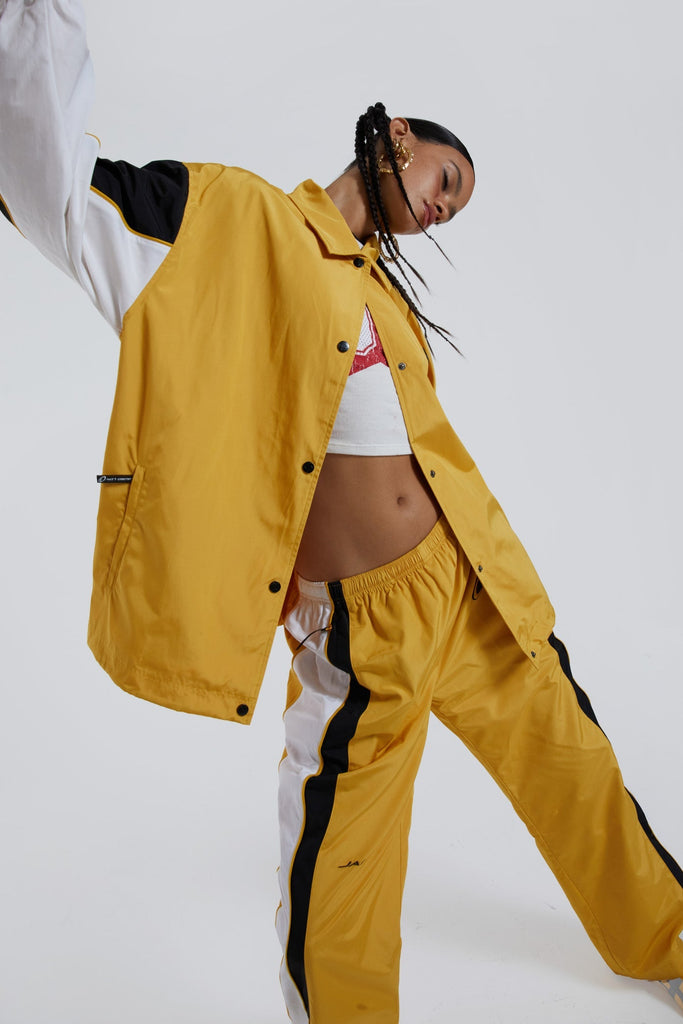 Female wearing yellow oversized track jacket with Jaded branding detail. Styled with the matching track pants. 