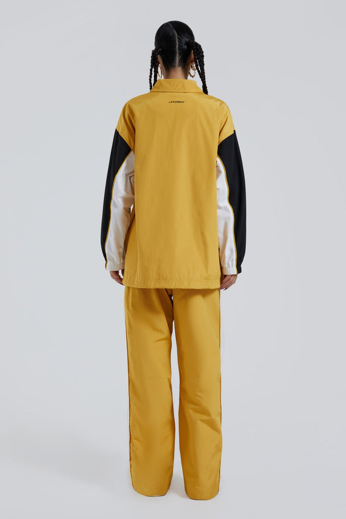 Female wearing yellow oversized track jacket with Jaded branding detail. Styled with the matching track pants. 