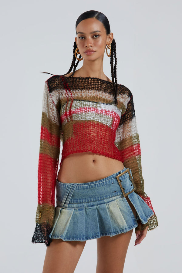 Female wearing blue pleated denim cut off mini skirt with oversized belt detail. Styled with multicoloured long sleeve knitted top. 