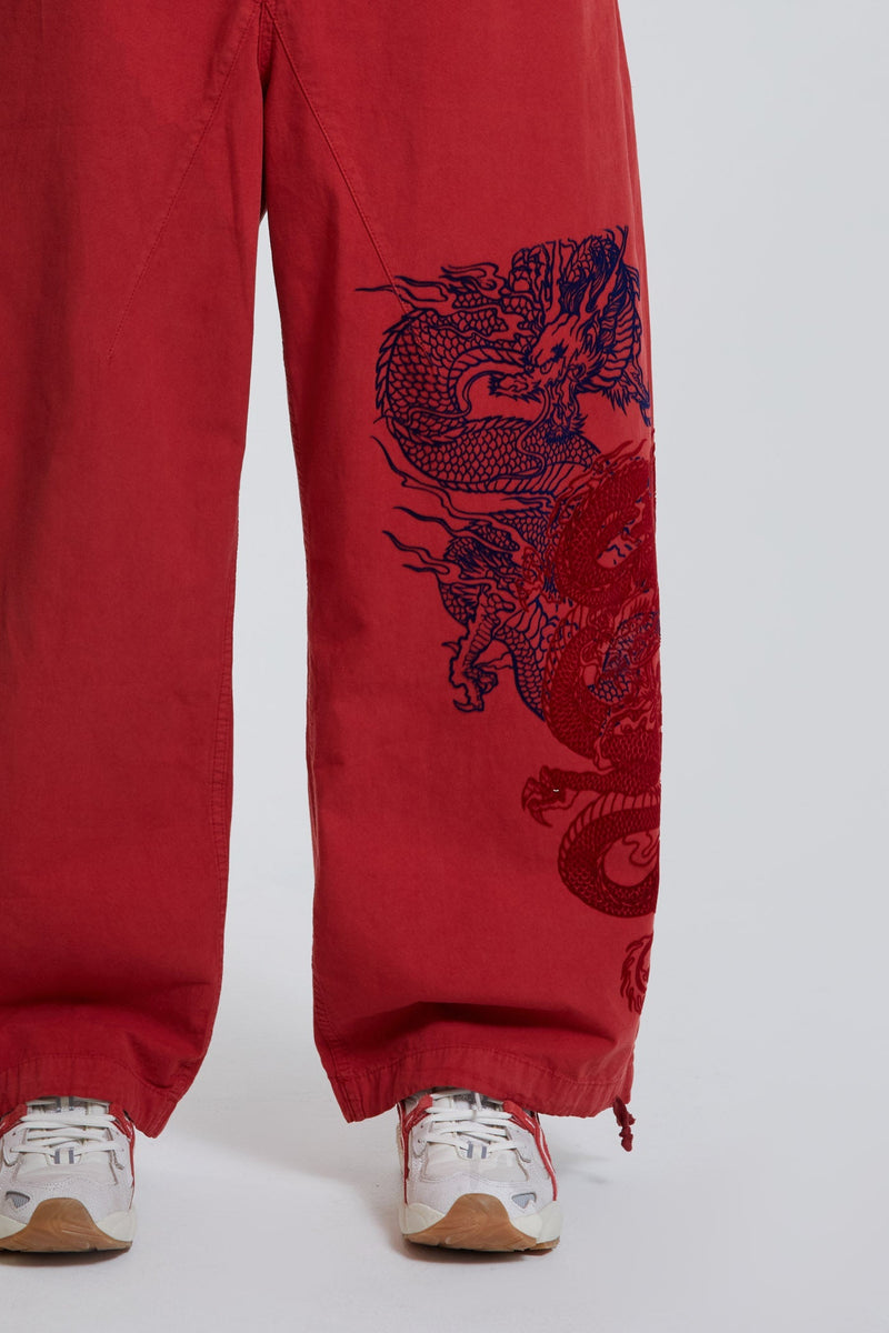 Female wearing red military cargo parachute pants with black dragon flock print. 