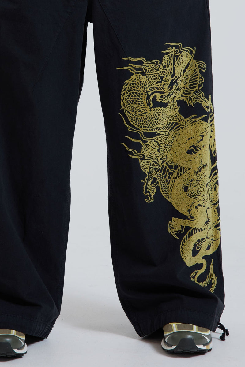 Female wearing black military cargo parachute pants with green dragon flock print. 