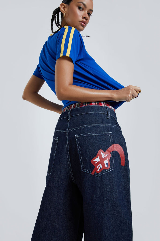 Female wearing sandblast washed denim oversized jorts in a jumbo fit with embroidered pocket patch detail. 