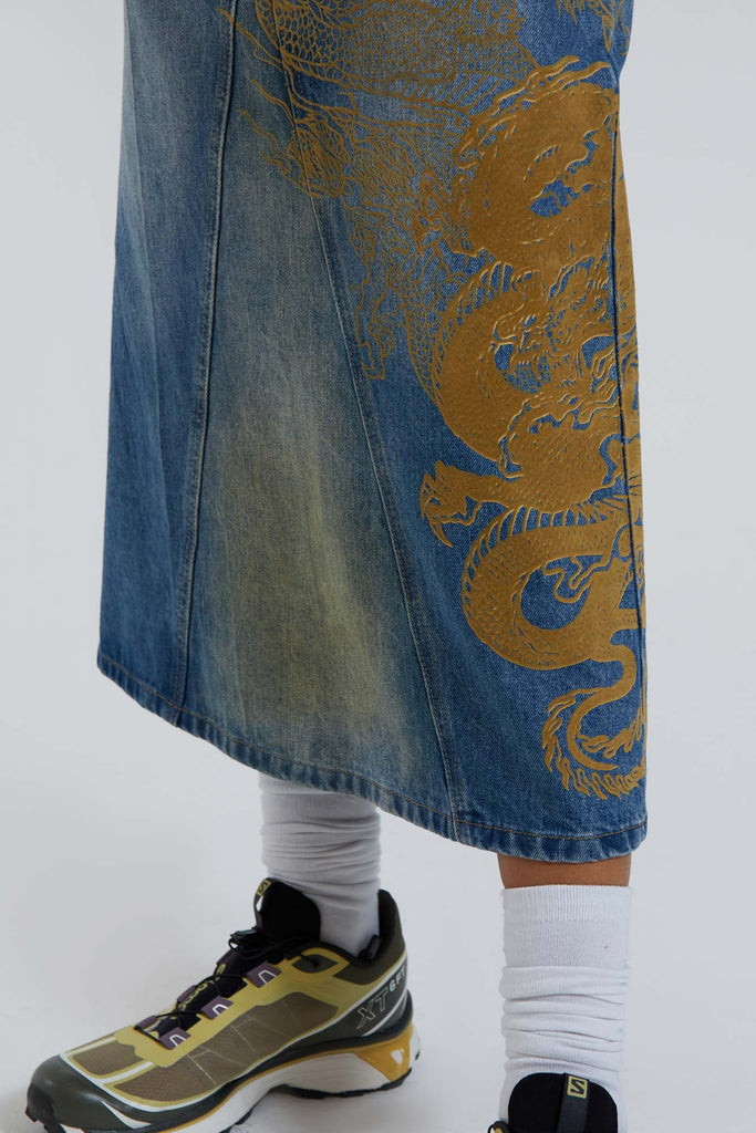 Female wearing sandblast washed denim 00's style maxi skirt with dragon flock print. 
