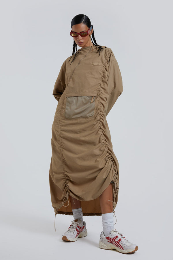 Female wearing stone khaki adjustable ruched detail maxi length long sleeve nylon jacket. 