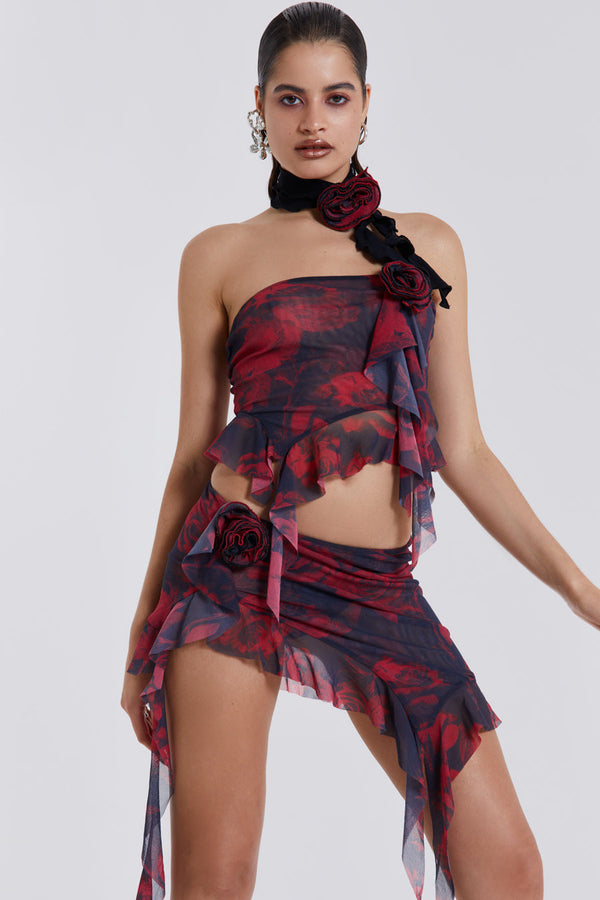 Female model wearing Dark Rose Print Asymmetric Bandeau Top. Styled with the matching asymmetric mini skirt and neck tie. 
