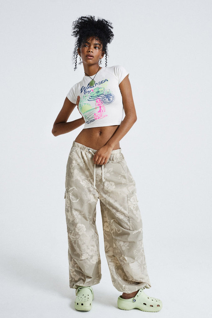 Female wearing Tonal Hawaiian Print Parachute Cargo Pants. Styled with white printed crop top.