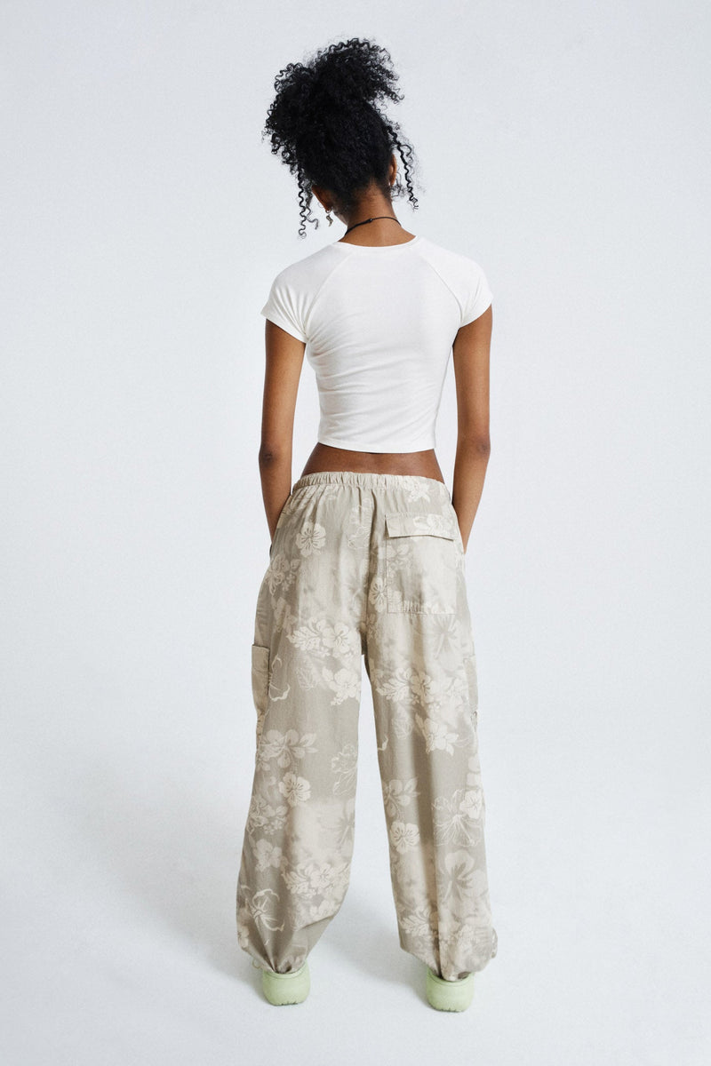 Female wearing Tonal Hawaiian Print Parachute Cargo Pants. Styled with white printed crop top.