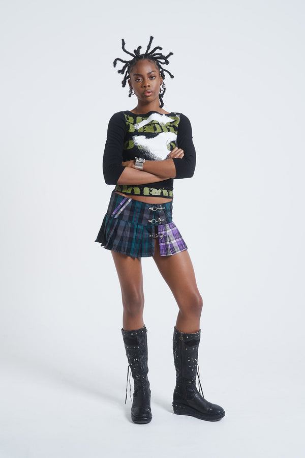 Female model wearing blue, green and purple checked mini kilt with pleats and buckle detail. 