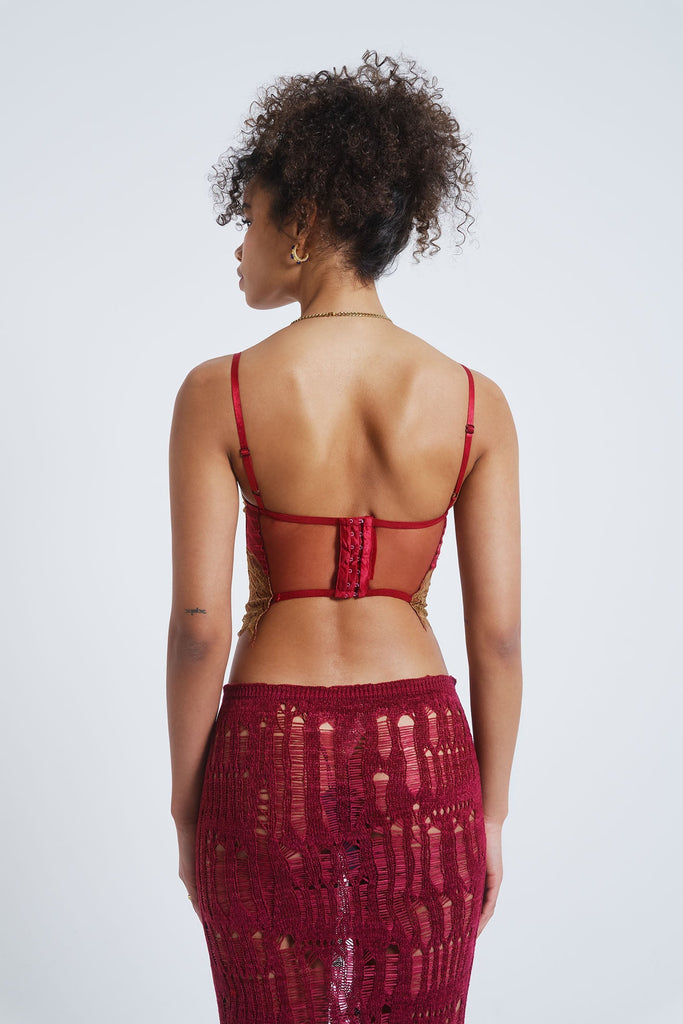 Female model wearing a red satin and mesh corset top with lace detail.  