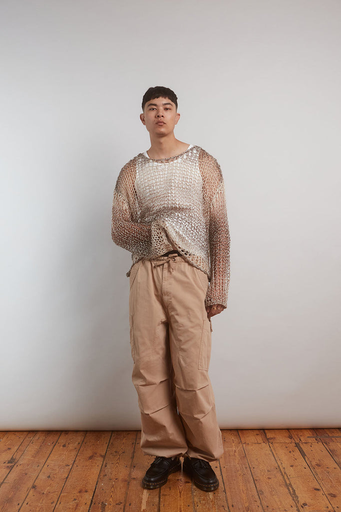 Male model wearing Gradient Loose Knit Jumper with stone trousers. 