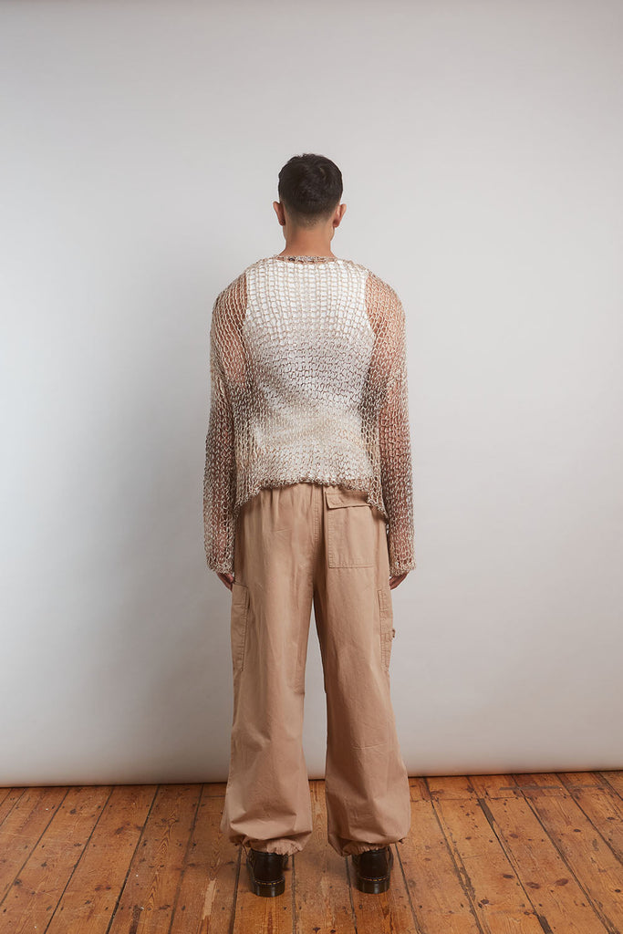 Male model wearing Gradient Loose Knit Jumper with stone trousers. 