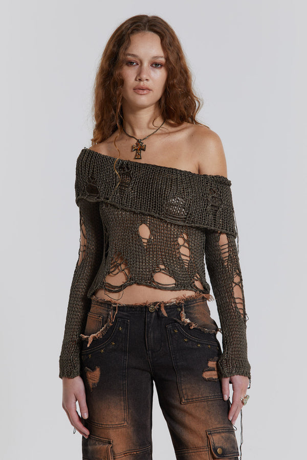Female model wearing a khaki green shredded knitted long sleeve off the shoulder top. Styled with black washed cargo jeans. 
