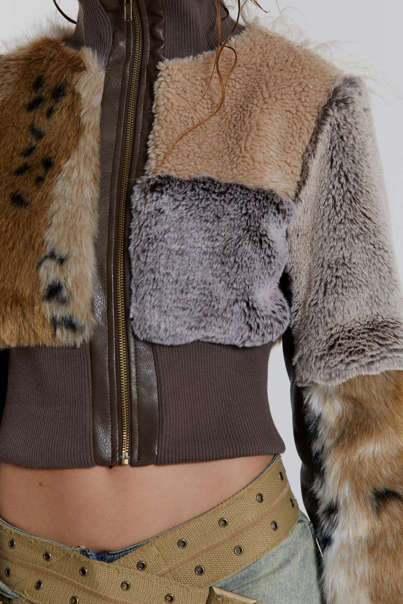 Female model wearing a patchwork faux fur bomber jacket with a ribbed collar and cuffs. 