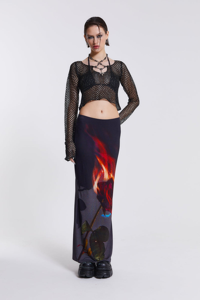 Female model wearing black sequin crochet top which features an attached beaded necklace. The flared sleeves and cropped length can be seen throughout the Vendetta collection. Paired with flaming rose print maxi skirt.