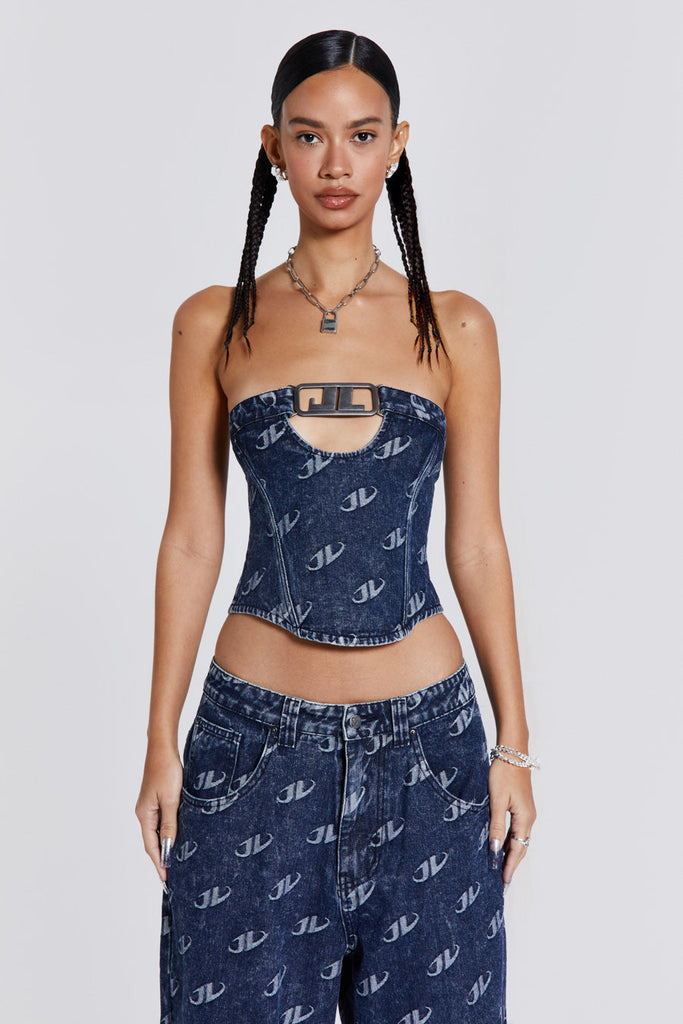 Female wearing a blue monogram embossed JL logo strapless corset top with a silver JL logo belt buckle detail. Styled with the matching baggy jeans. 