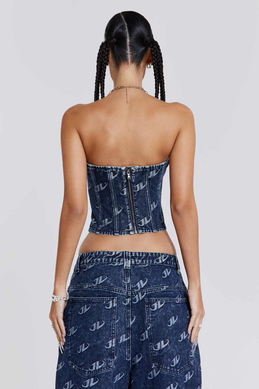 Female wearing a blue monogram embossed JL logo strapless corset top with a silver JL logo belt buckle detail. Styled with the matching baggy jeans. 